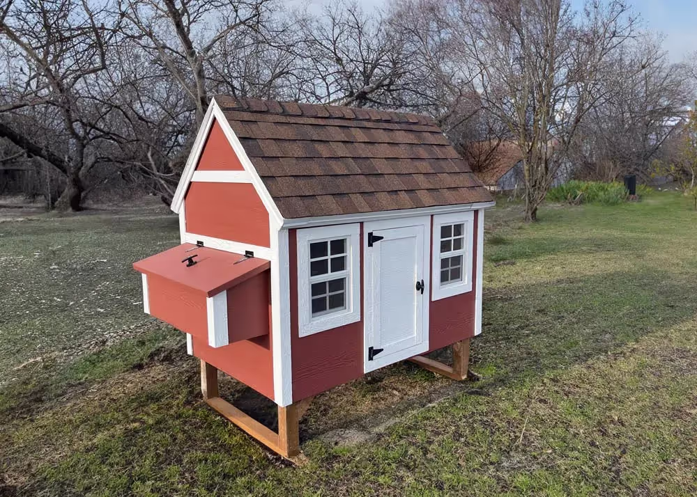 A large red and white hen hut chicken coop in a field