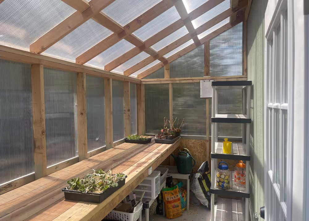 The interior of a green house shed combo with a redwood workbench