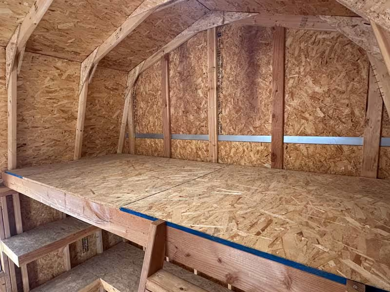 The interior of a tall barn shed with a loft on top of the walls.
