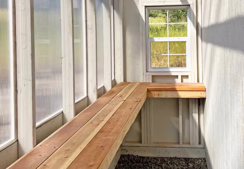Greenhouse interior with a sturdy redwood workbench, providing durable workspace for gardening and potting.