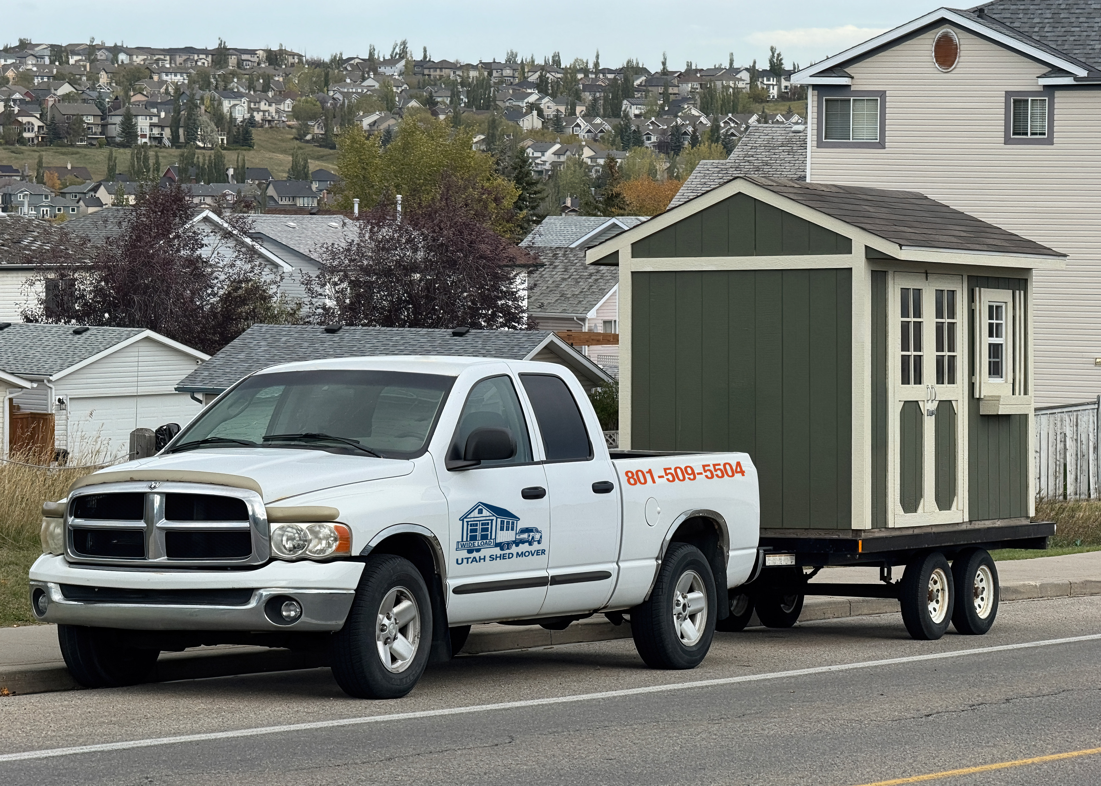 A truck moving a storage shed on a trailer