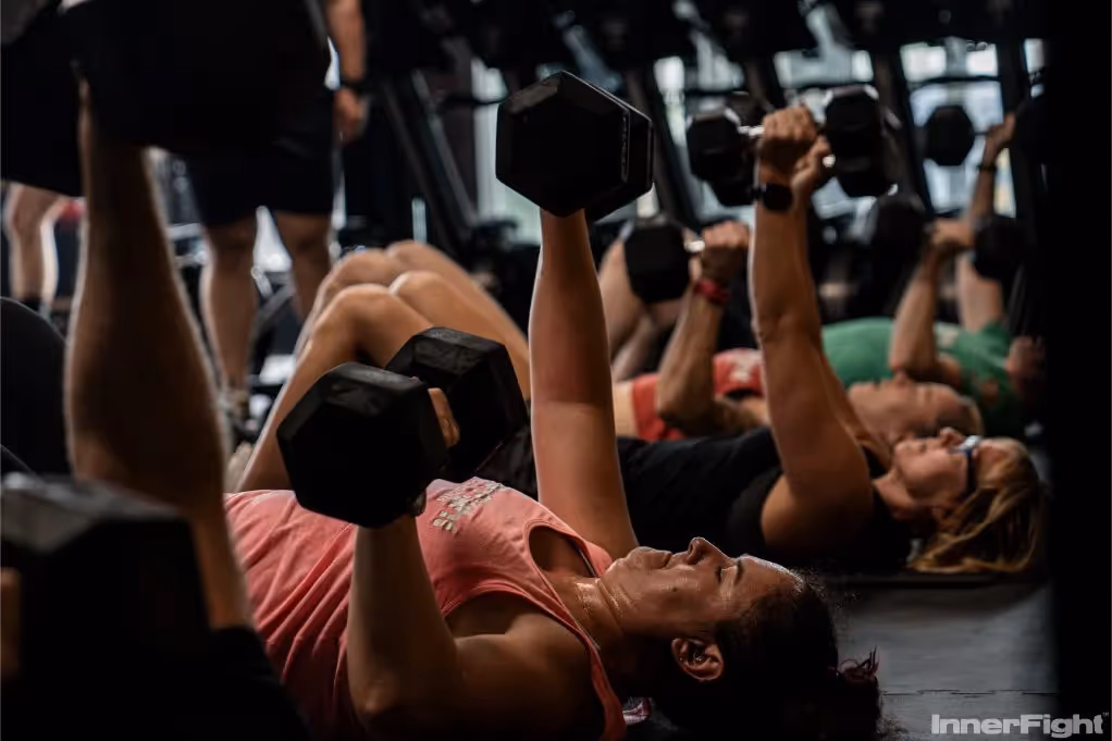 Group fitness class focusing on dumbbell press technique