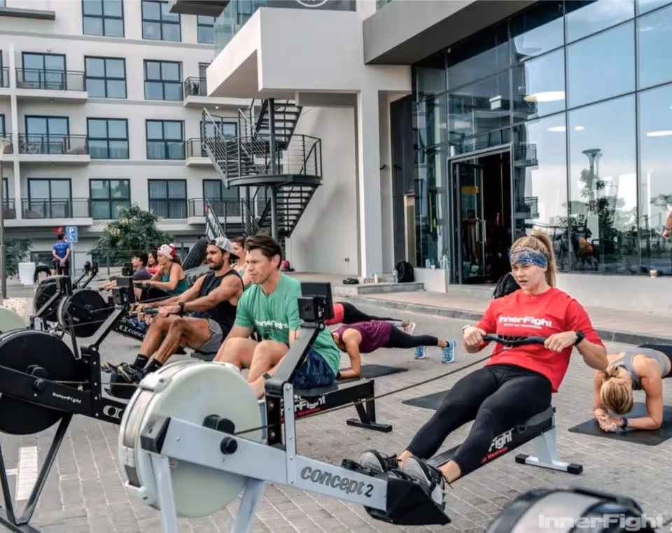 Group fitness class taking part on Concept2 rowing machines outside a gym