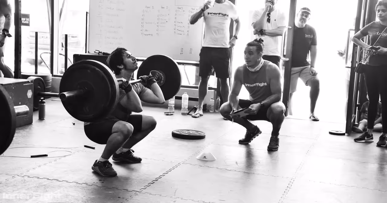 Group CrossFit workout class with barbell squat thrusters