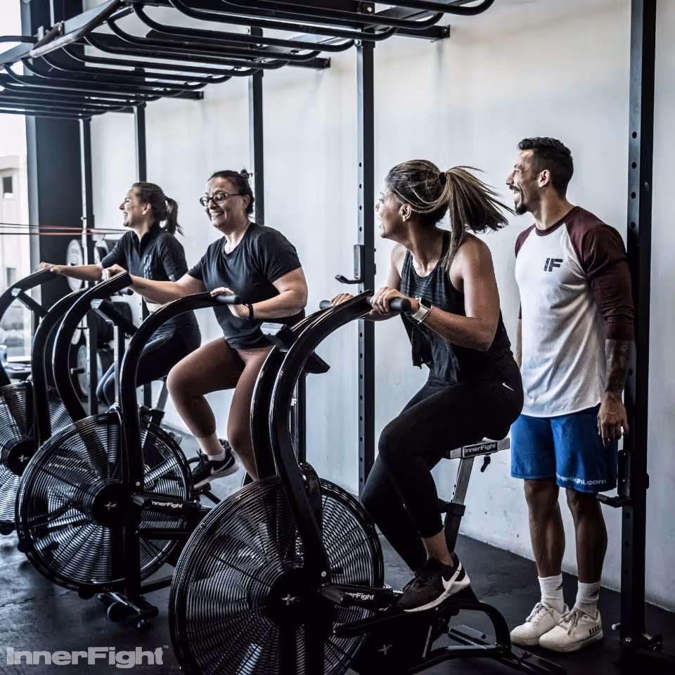 A group of smiling individuals participating in a beginner CrossFit class, focusing on proper form and technique.