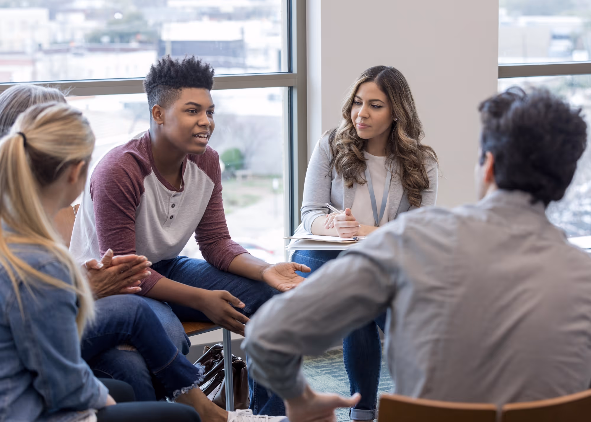 A group of co-workers sitting in a circle while paying attention to the one person speaking to the group sharing their perspective at a C2K training.