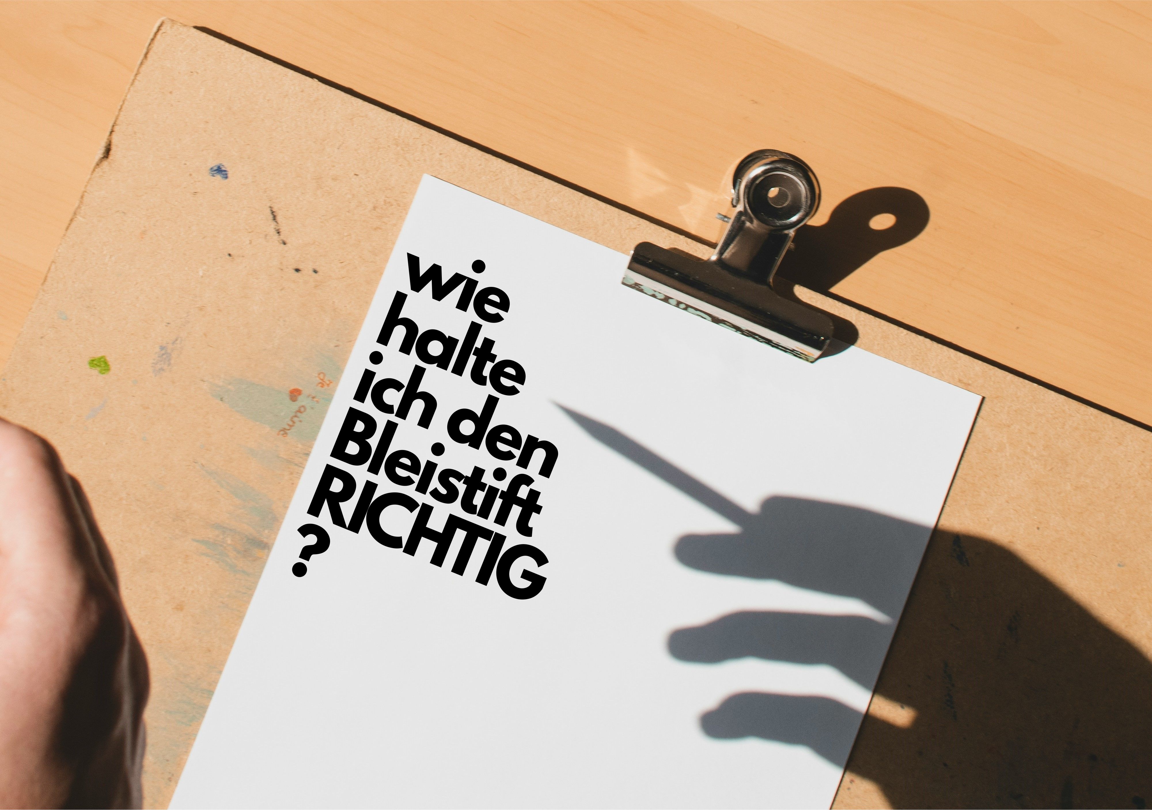 Ein Blatt Papier und der Schatten einer Hand mit Bleistift