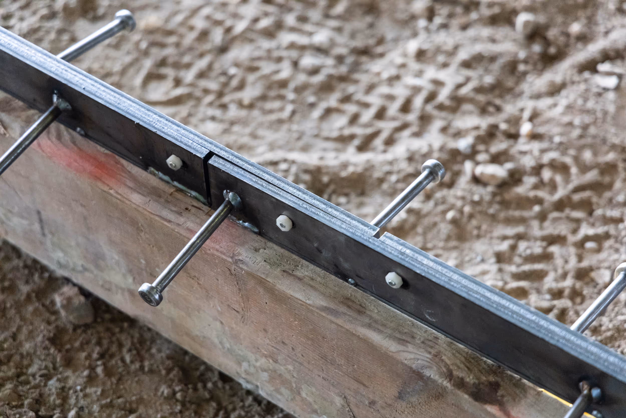Iron-Clad joint assemblies by American Highway installed in commercial flatwork, showcasing high-tolerance steel bars and nylon nuts for spall-free concrete joints.