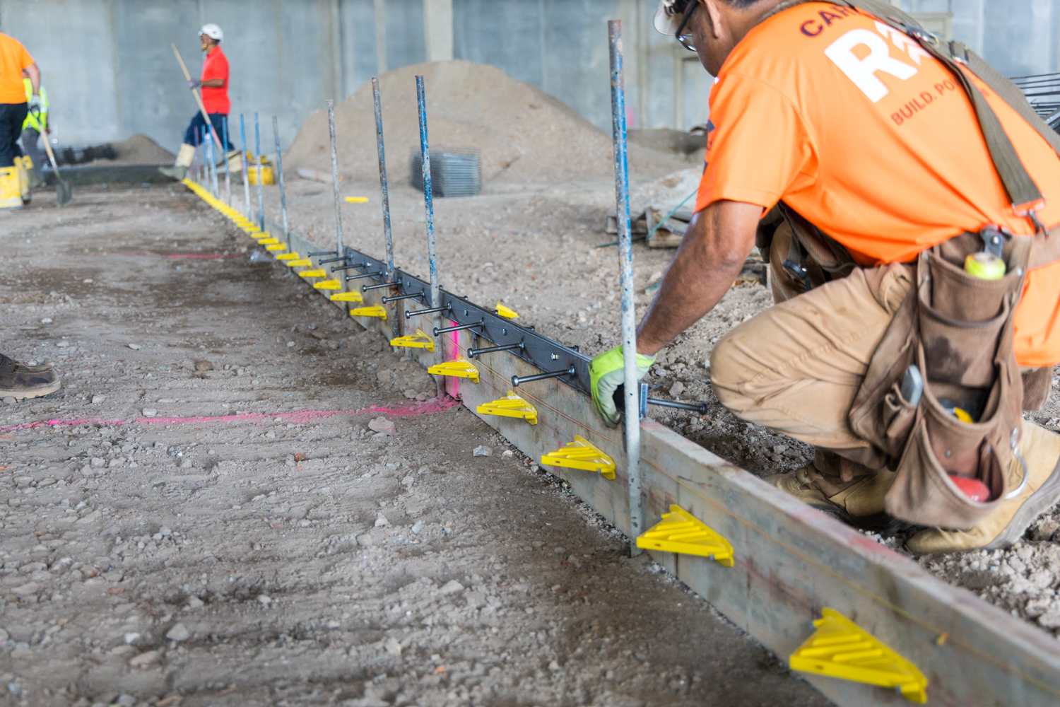 Iron-Clad joint assemblies by American Highway installed in commercial flatwork, showcasing high-tolerance steel bars and nylon nuts for spall-free concrete joints.