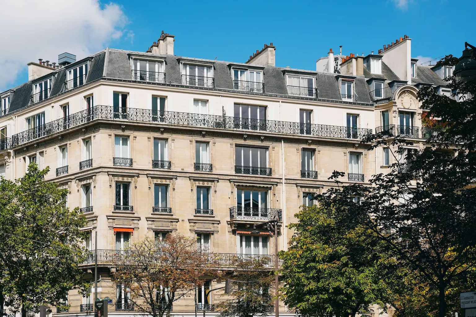 Immeuble haussmannien avec des arbres sous un ciel lumineux