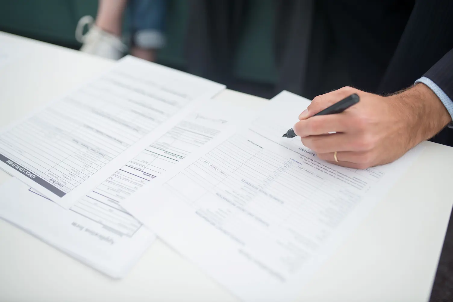 Gros plan d'une main signant des documents dans un cadre de bureau.
