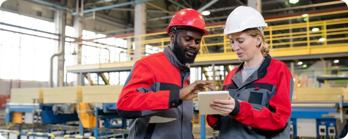 a man and a woman in hardhats looking at a tablet