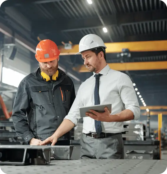 two men in hardhats looking at a tablet