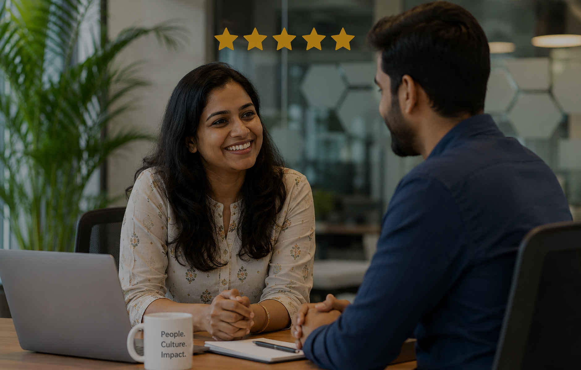 Smiling woman and man having a friendly meeting with a laptop and a mug on the table.
