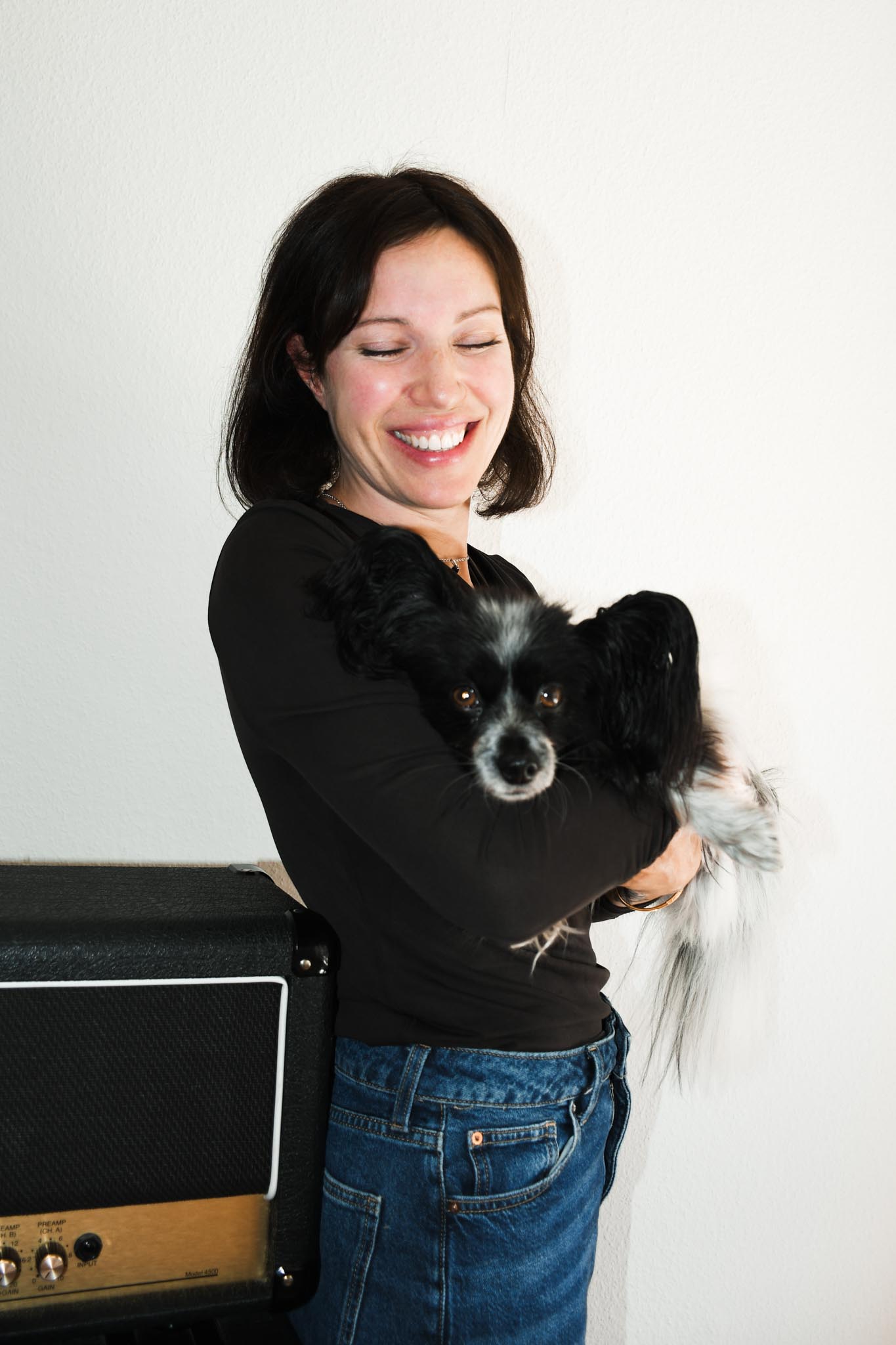 Désirée and her dog in front of a white wall in the office.
