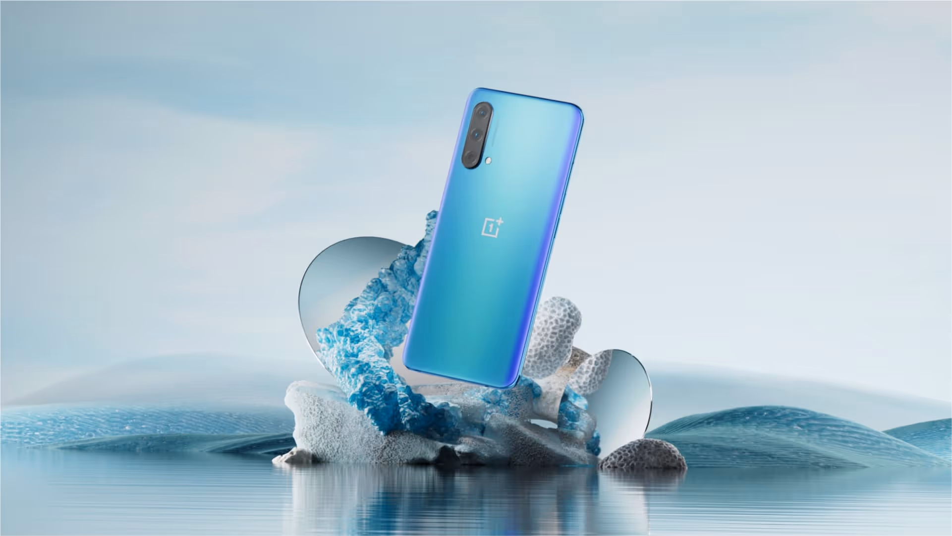 OnePlus device sits on an arrangement of rocks and other assets in a still life composition.
