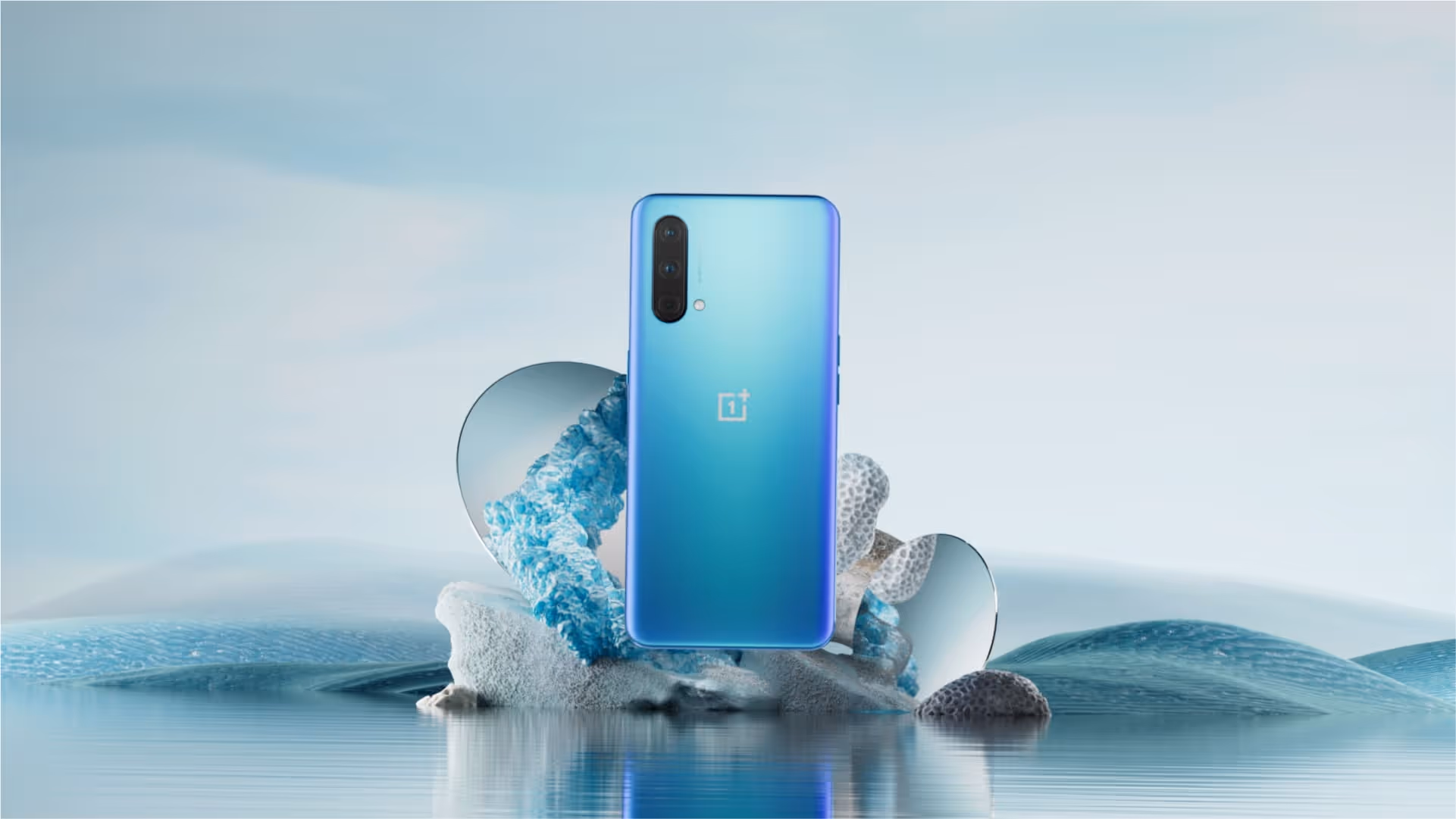 OnePlus device sits on an arrangement of rocks and other assets in a still life composition.
