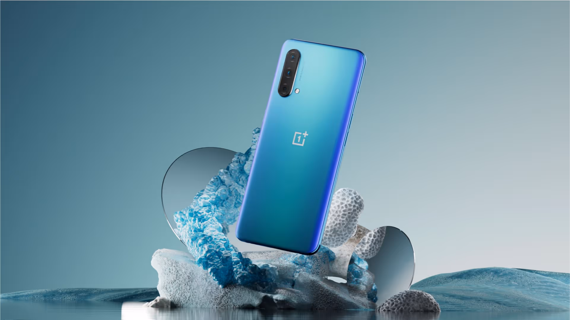 OnePlus device sits on an arrangement of rocks and other assets in a still life composition.
