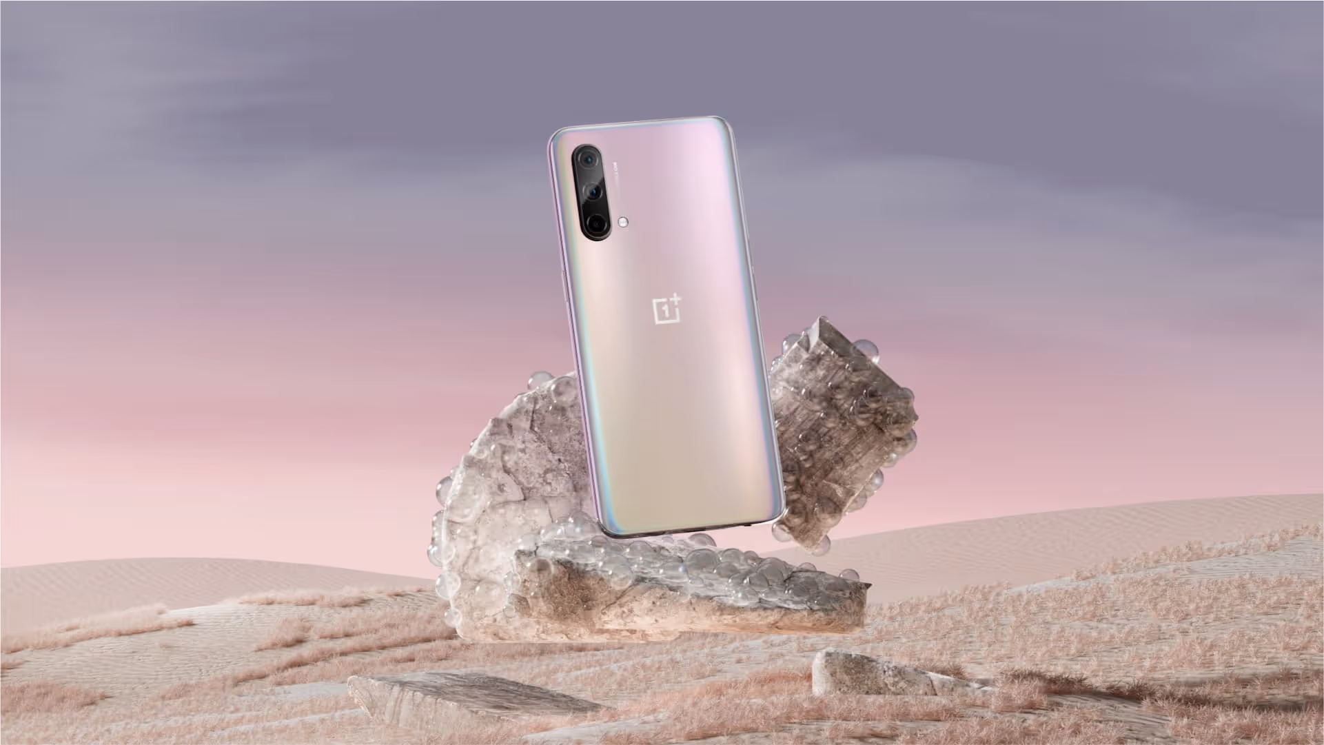 OnePlus device stands on an arrangement of rocks set against a pink and lilac background.