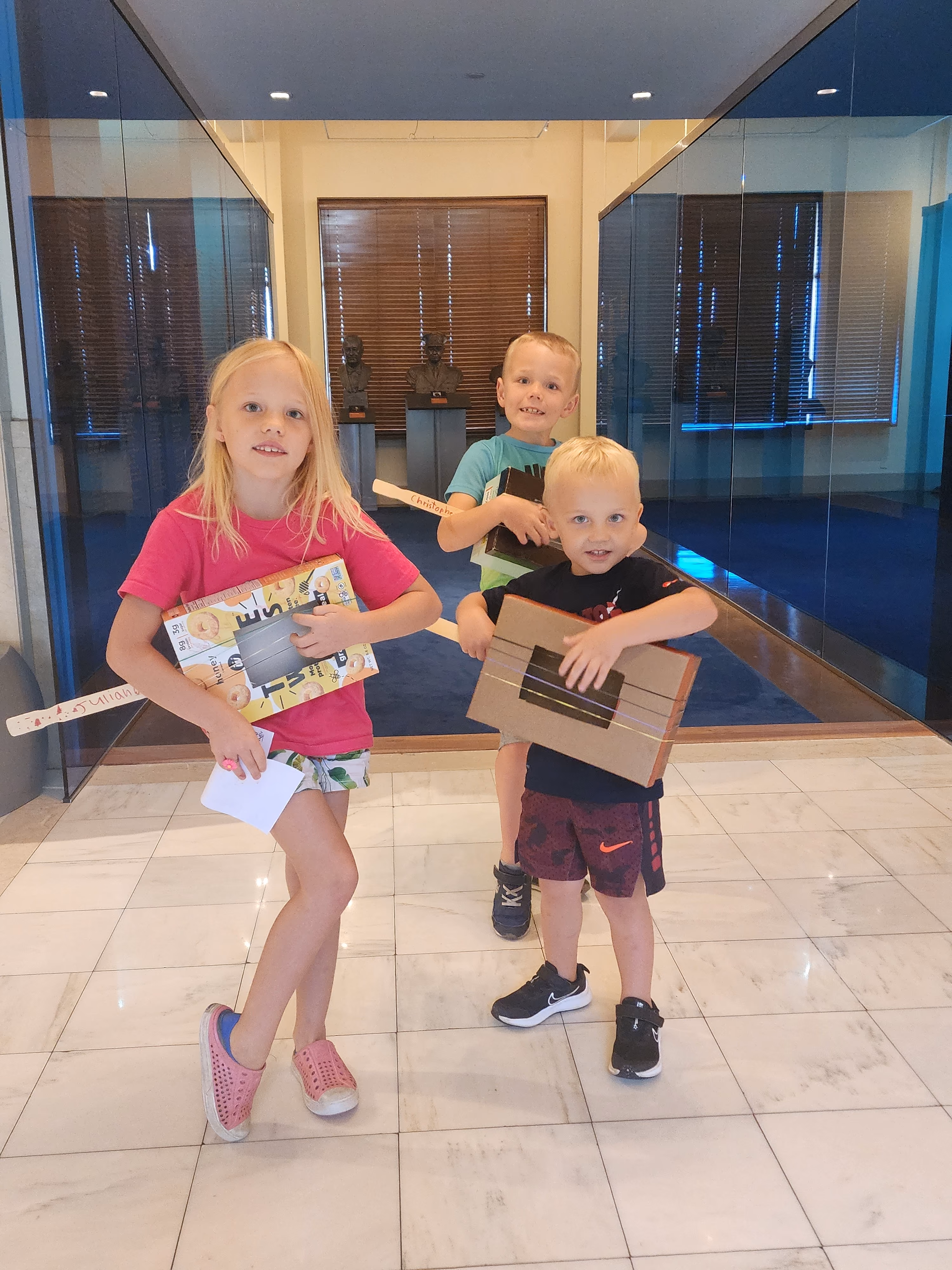A family of two boys and one girl play the guitars they created out of cereal boxes and rubber bands at a music themed Homeschool Day.