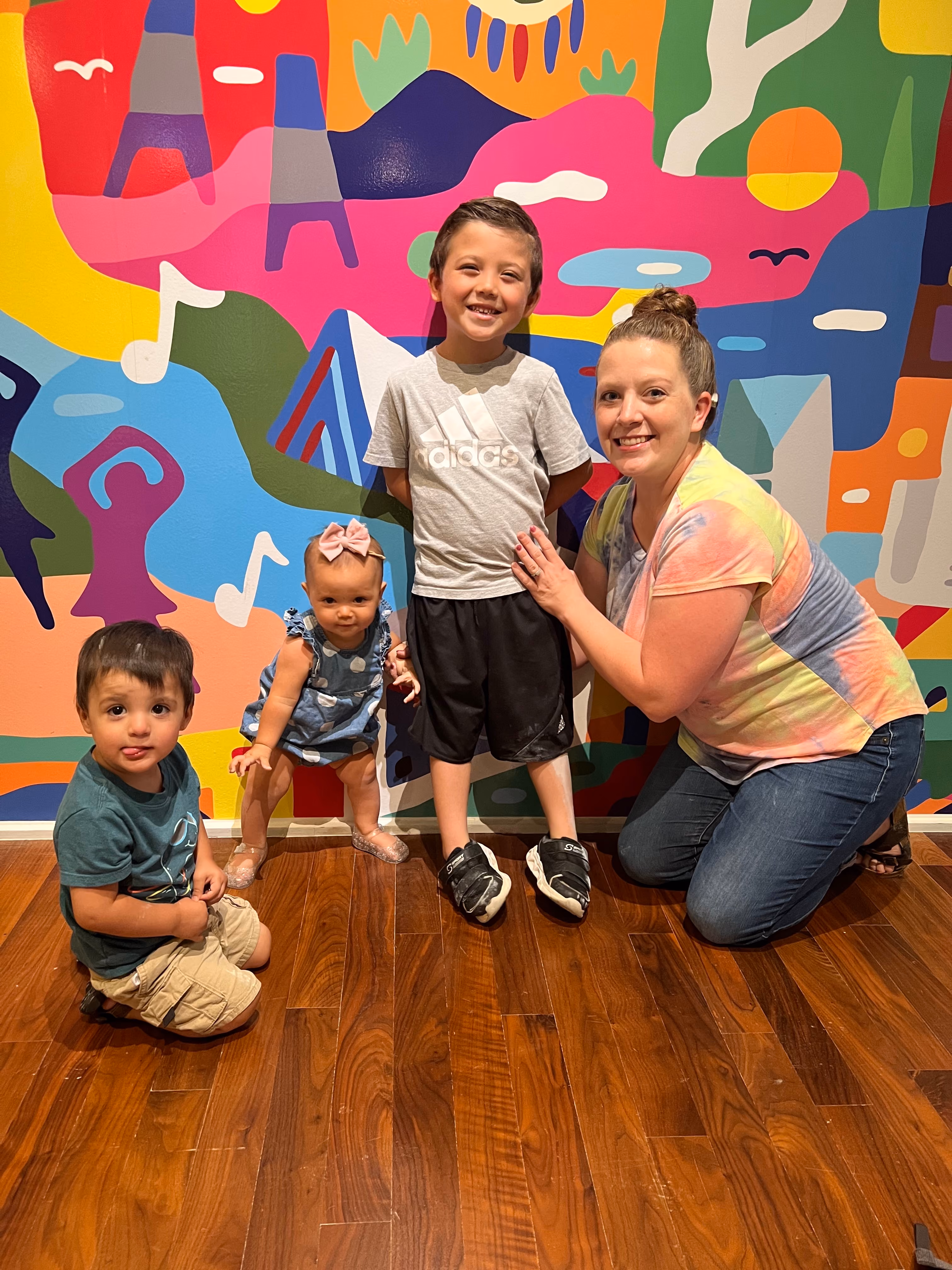 A mother with her three young children stand in front of the Kris Kanaly art mural in the museum.