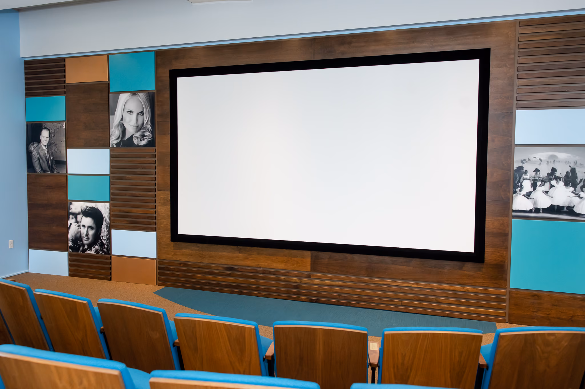 The interior of the Chesapeake Oklahoma Theatre features a large screen for movie screenings, presentations, or speaking engagements. The screen is surrounded by panels of wood and black and white photos of Oklahoma Hall of Fame members.