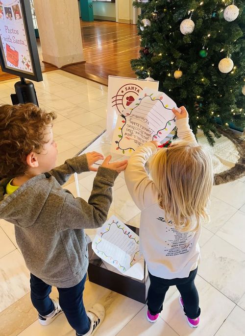 A brother and sister put the letters to Santa that they wrote into a mailbox to be sent to the North Pole.