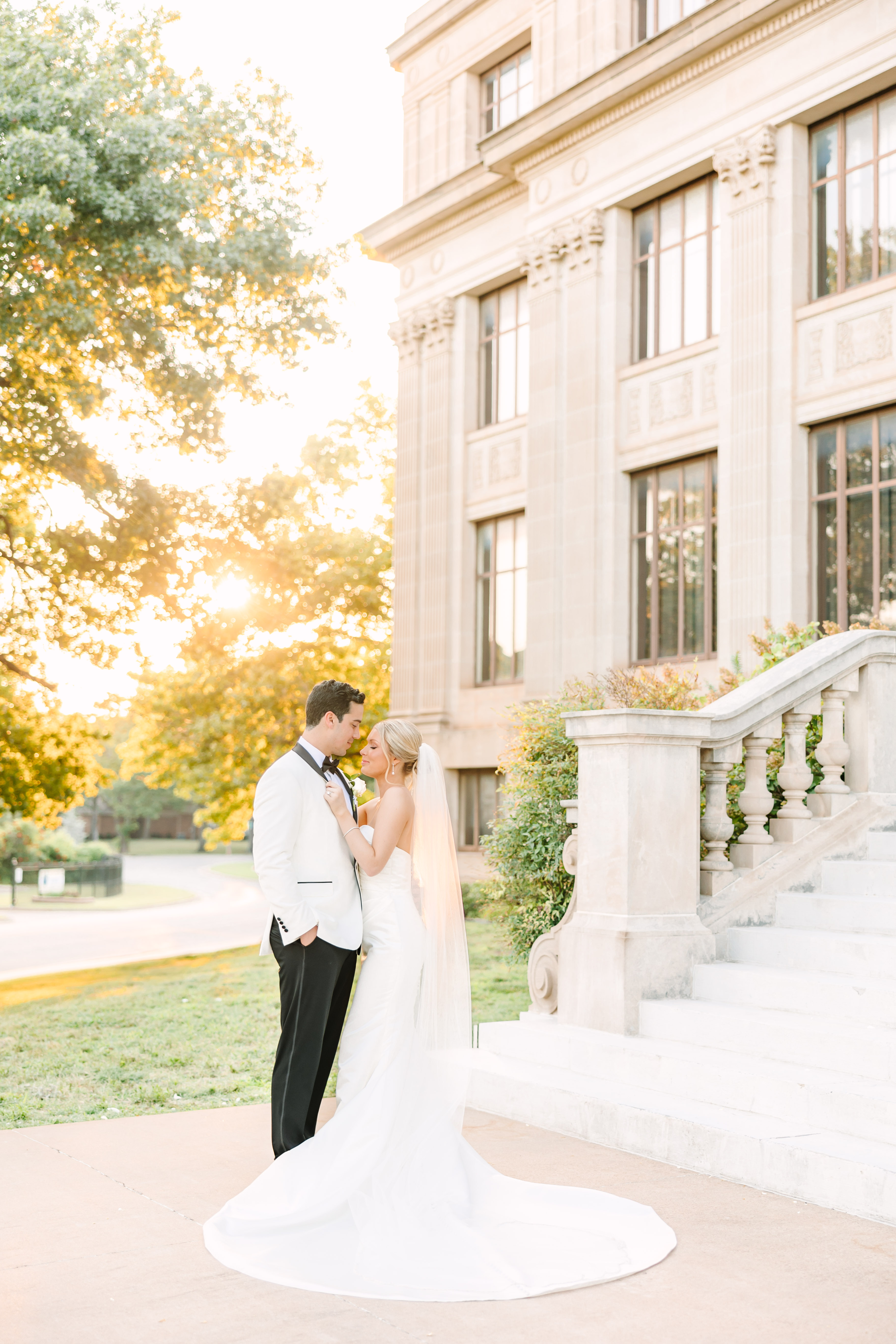 A bride and groom stand together in front of the Oklahoma Hall of Fame building.