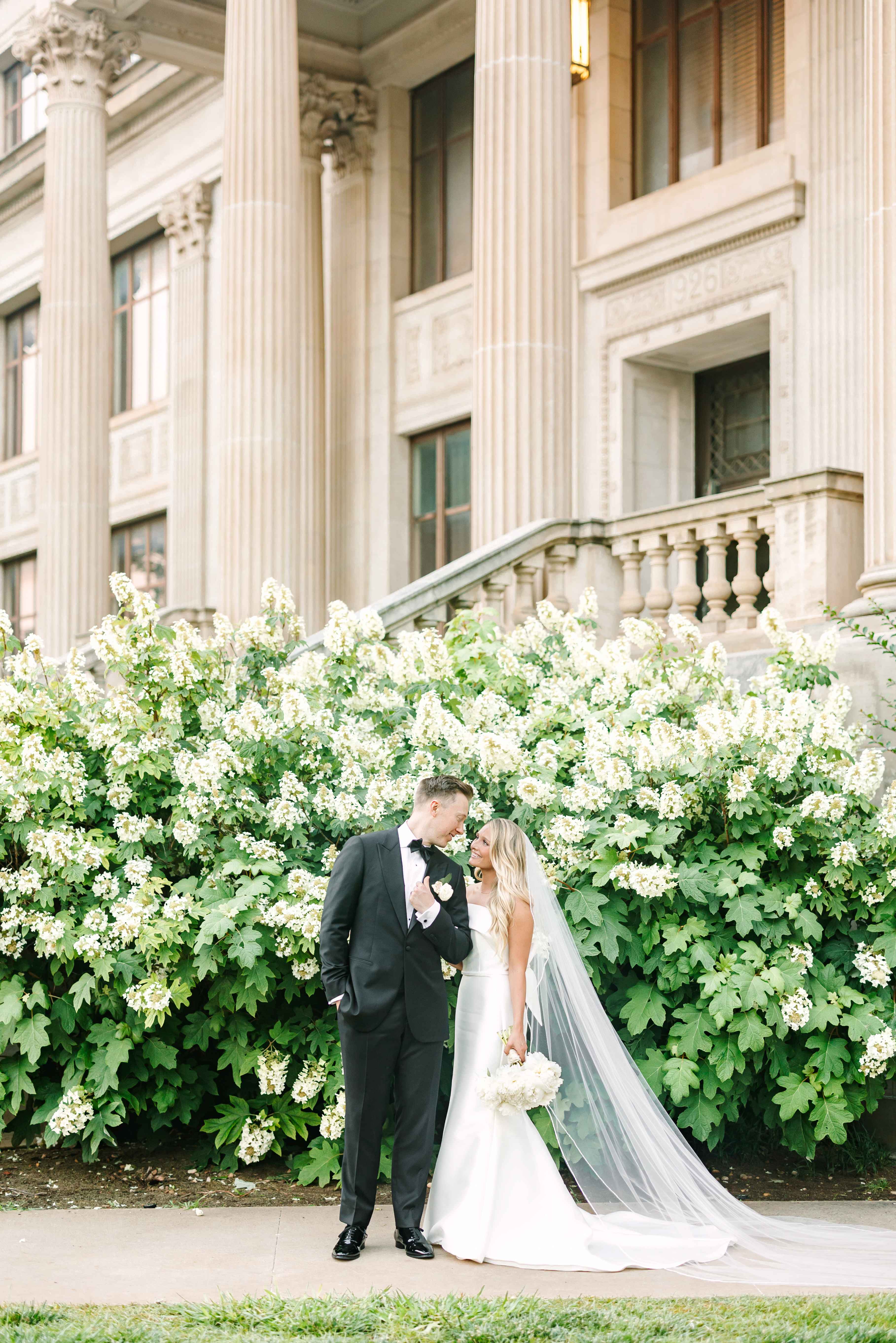 A bride and groom pose in front of the Oklahoma Hall of Fame.