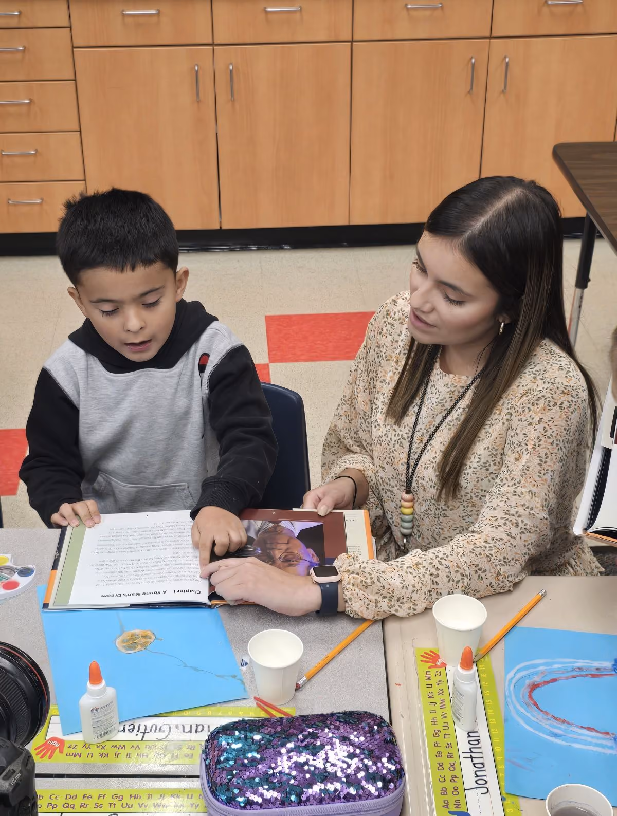 An elementary school teacher helps one of her students with the salt art activity.