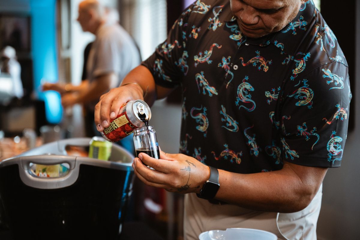 A brewer pours a beer sample into a tasting glass.