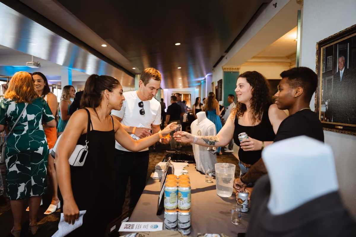 A brewer hands an attendee a tasting glass full of beer.