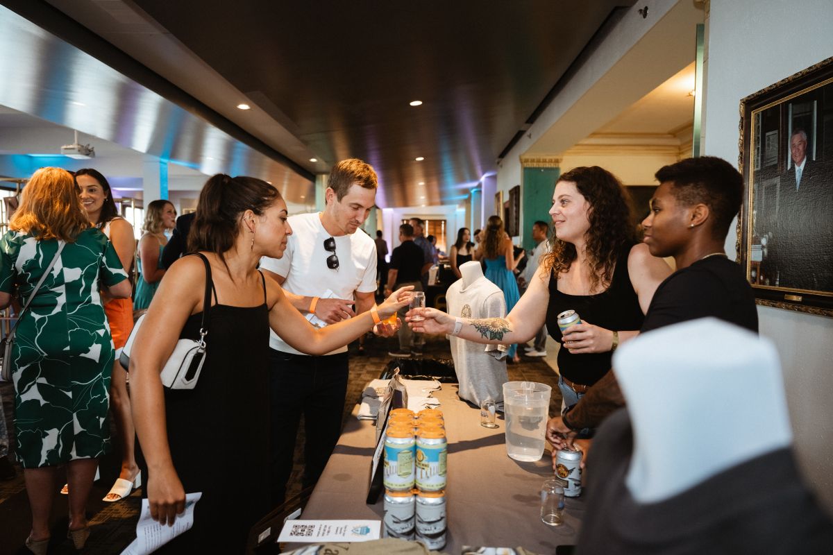 A brewer hands an attendee a tasting glass full of beer.