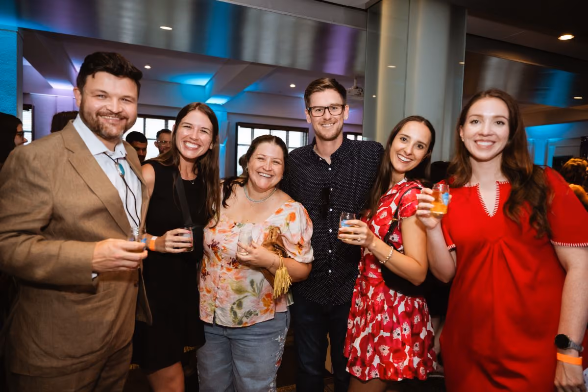 A group of six attendees gather for a photo, while holding taster glasses.