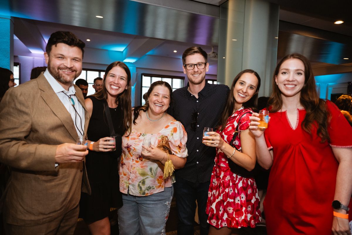 A group of six attendees gather for a photo, while holding taster glasses.
