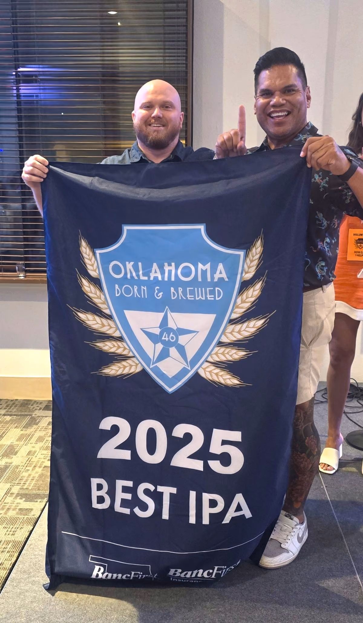 Two guys from Roughtail Brewery hold up their Best IPA award banner.