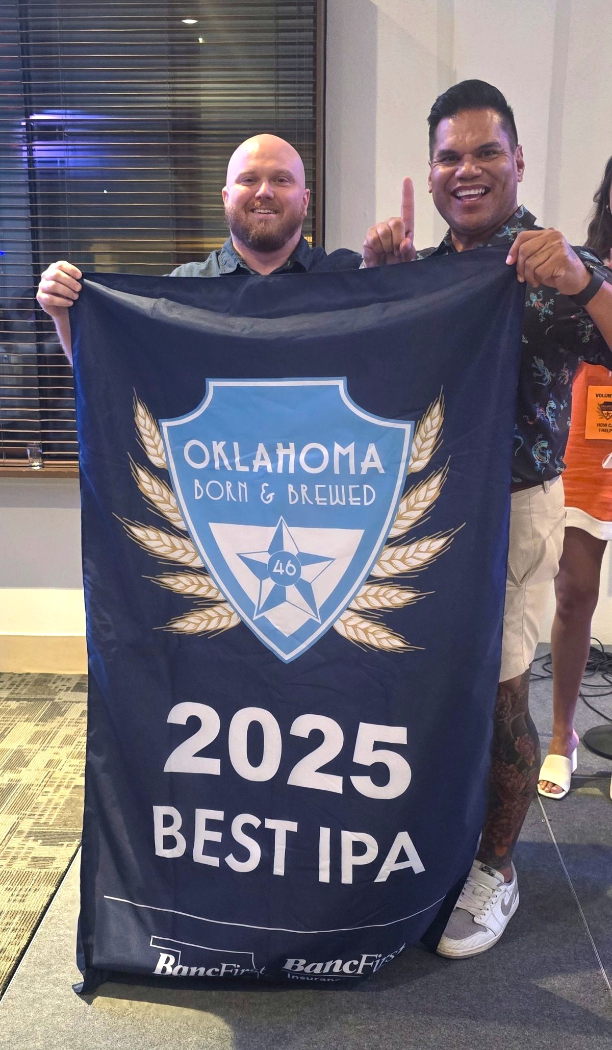 Two guys from Roughtail Brewery hold up their Best IPA award banner.