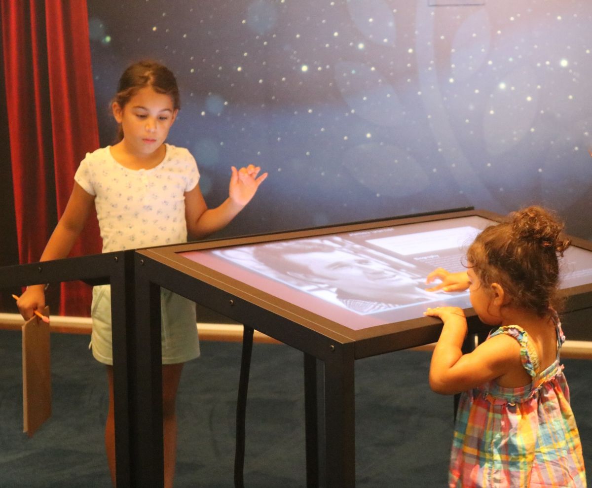 Two young girls use the ADA accessible tablets in the Interactive Inductee Gallery.