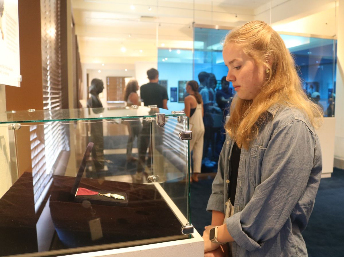 A high school student looks at an Oklahoma Hall of Fame Medallion inside a glass case.