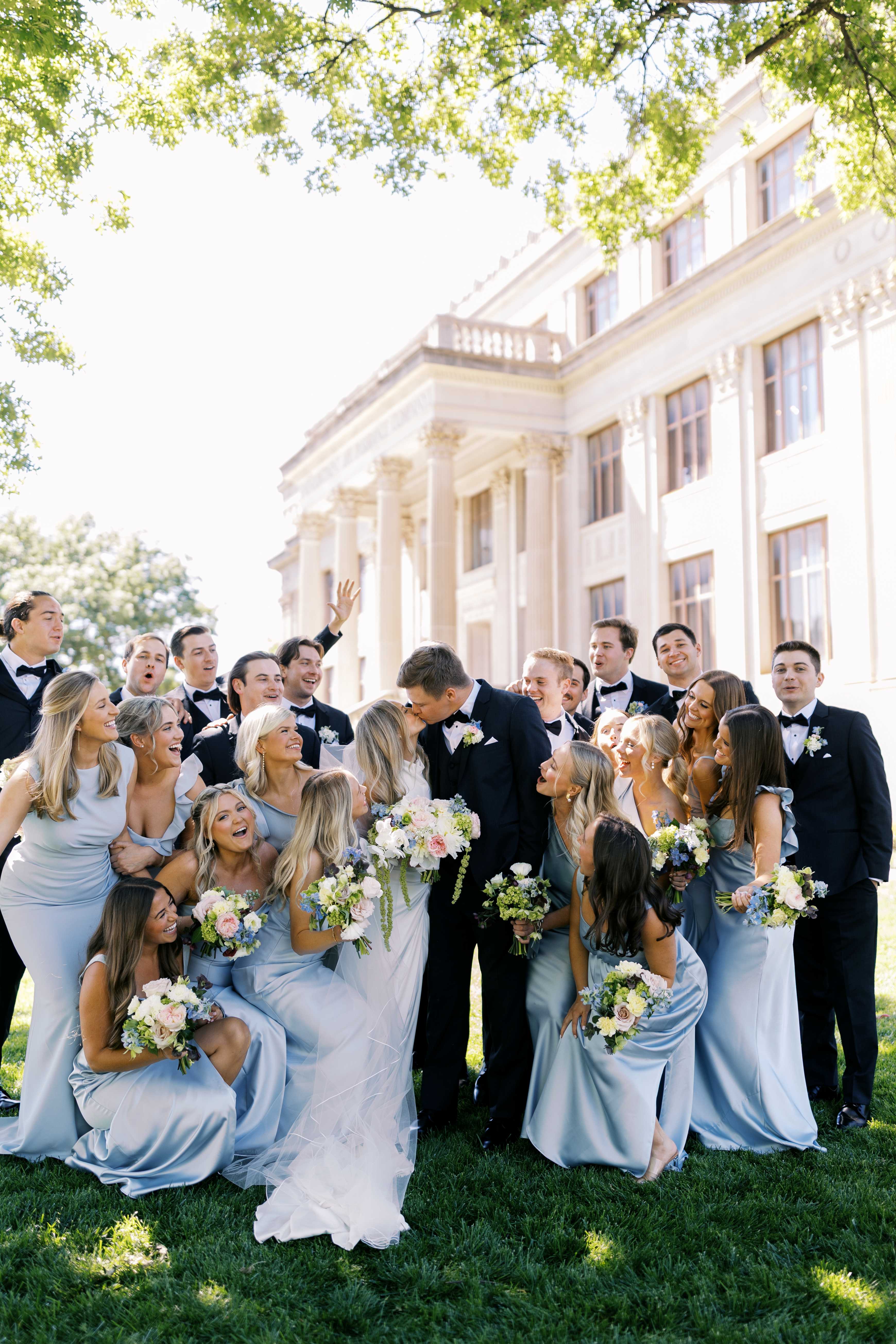 A wedding party poses around the bride and groom in front of the Oklahoma Hall of Fame