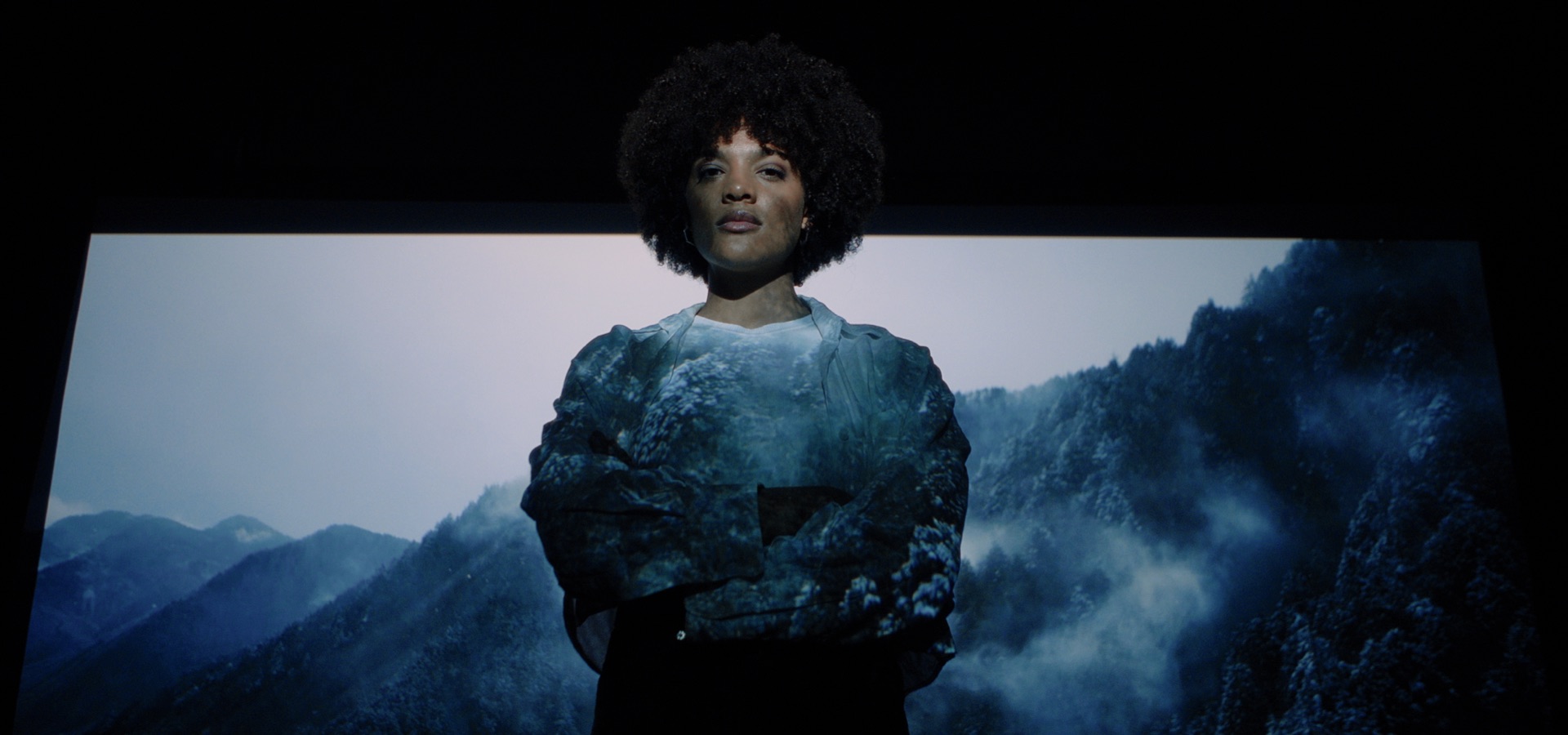 Young woman illuminated by projection of a winter landscape