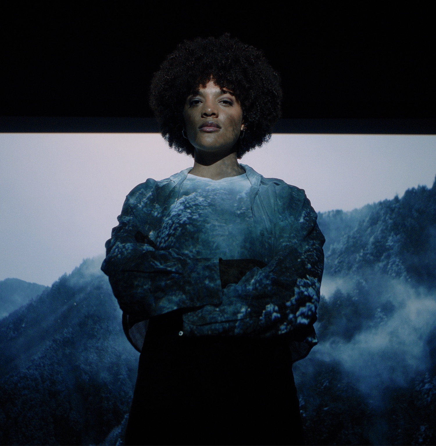 Young woman illuminated by projection of a winter landscape