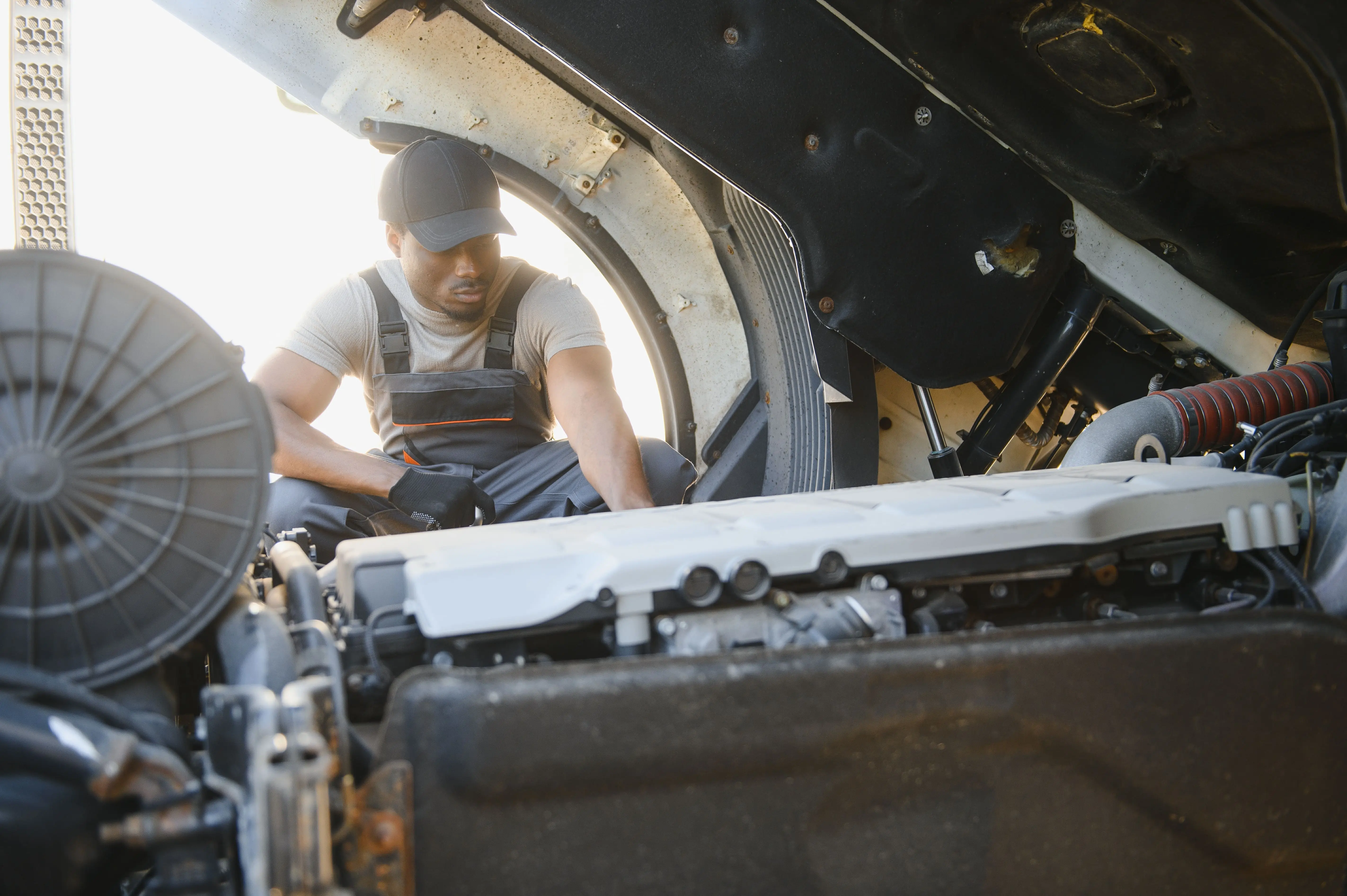 Truck driver inspecting vehicle for early mechanical failure signs