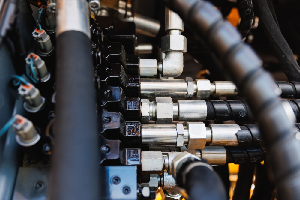 Technician inspecting a hydraulic hose and fitting on heavy equipment in Edmonton, Alberta