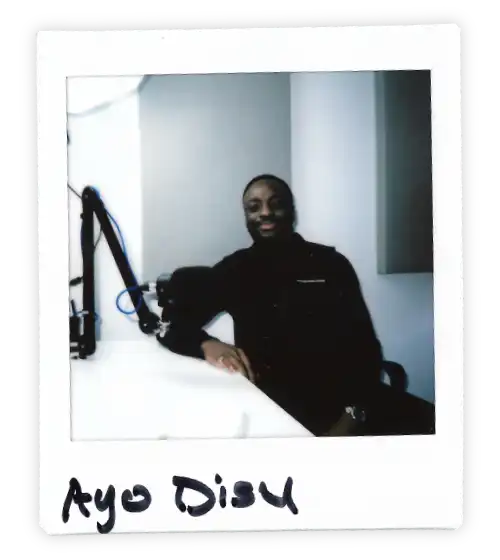 Polaroid of Ayu Disu in the Oxford Podcast Studio sat at the table with a microphone.