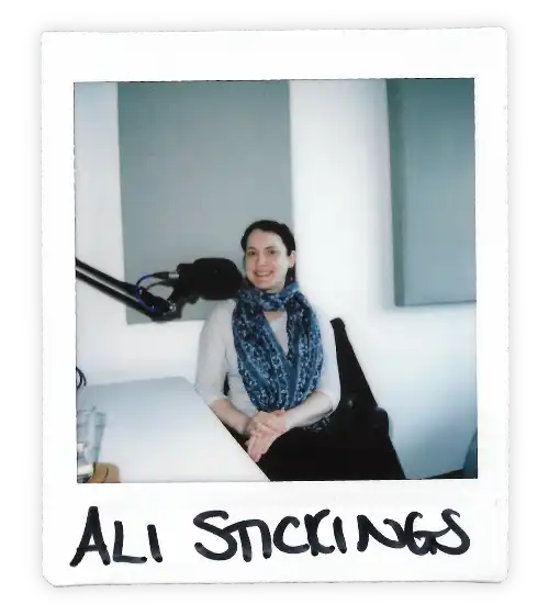 Polaroid of Ali Stickings in the Oxford Podcast Studio sat at the table with a microphone.