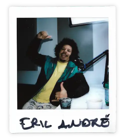 Polaroid of Eric Andre in the Oxford Podcast Studio sat at the table with a microphone.