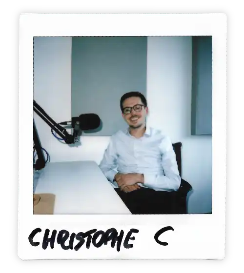 Polaroid of Christophe C in the Oxford Podcast Studio sat at the table with a microphone.