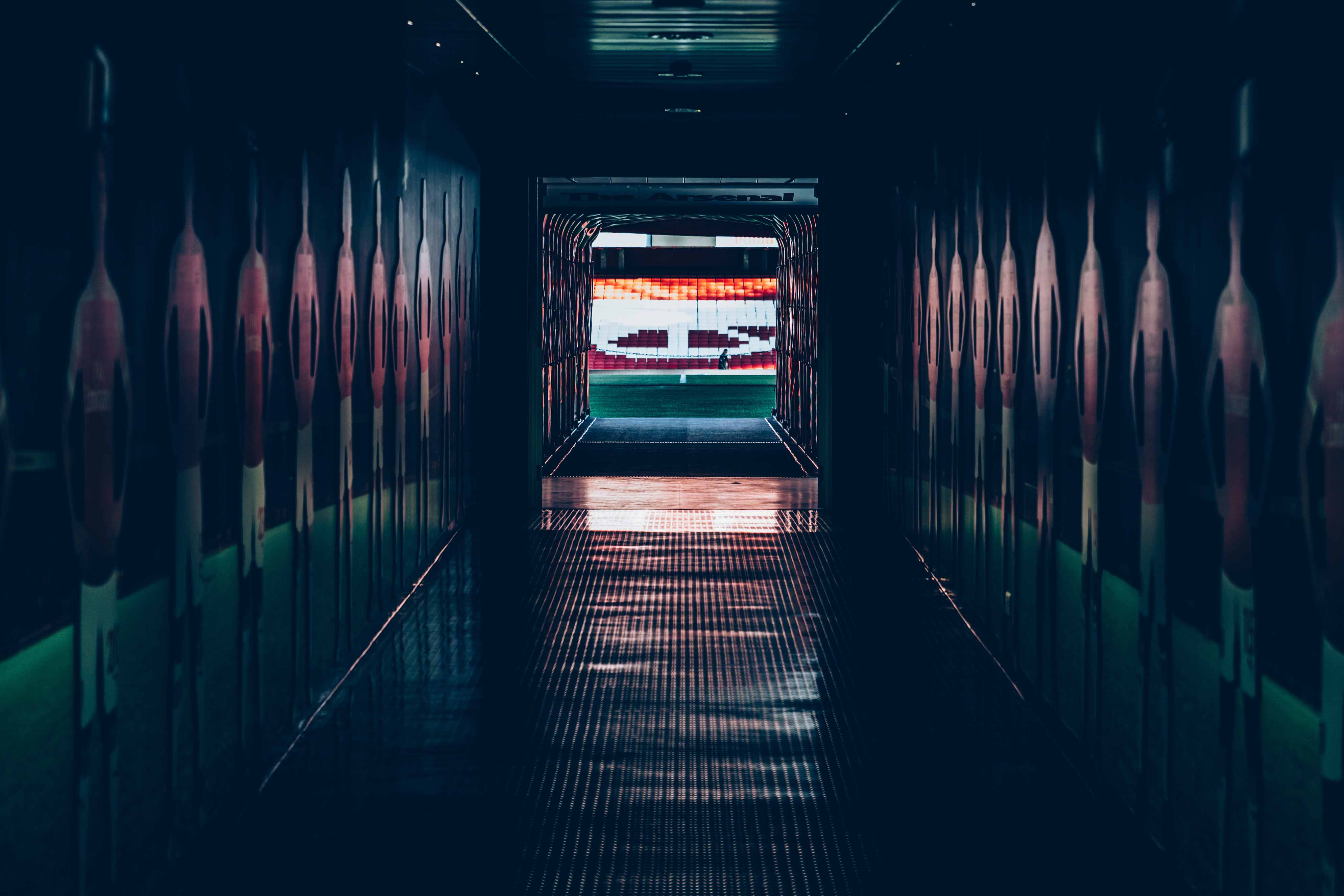 Dark player tunnel leading out to a football pitch