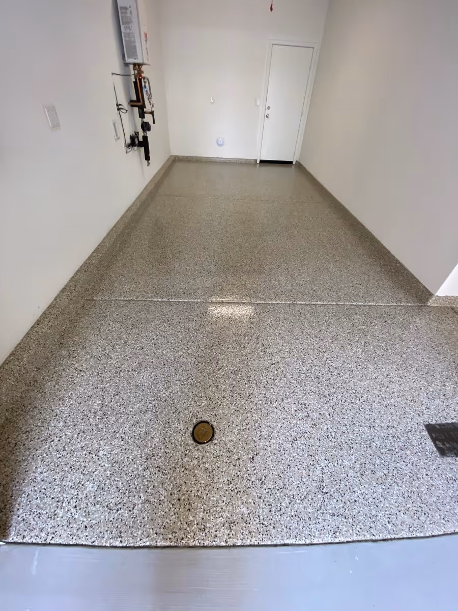 Empty garage with newly installed speckled epoxy floor coating and white walls.
